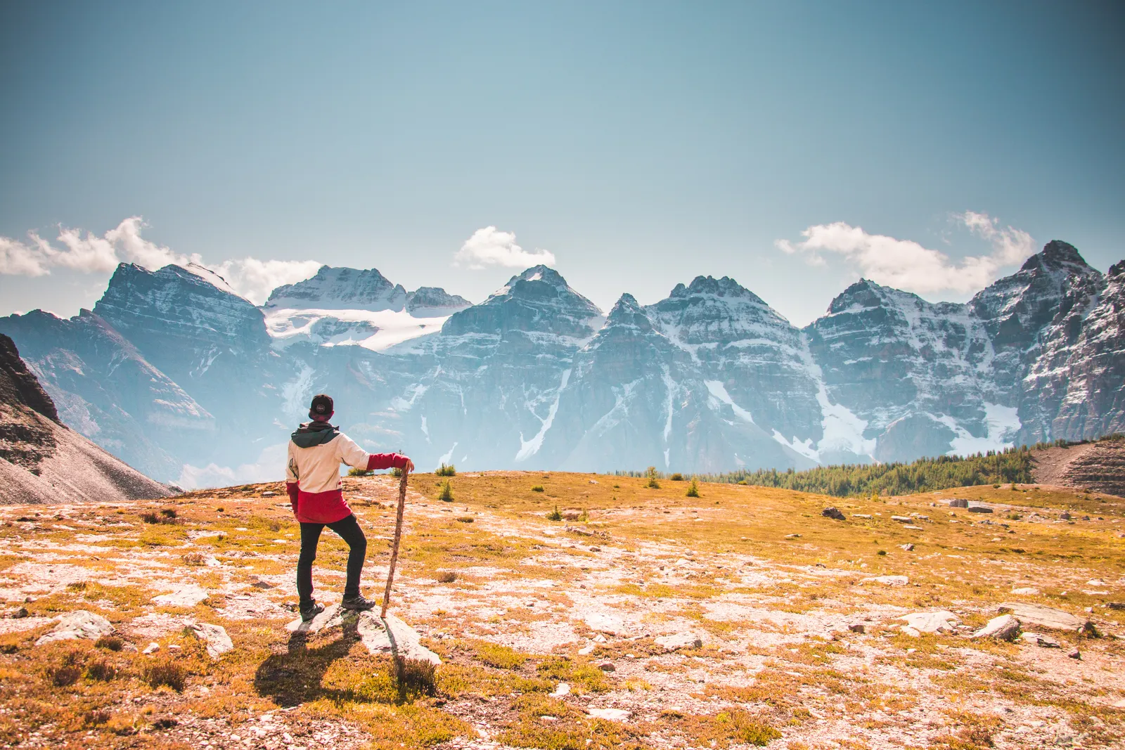 A hiker on a high viewpoint above a broad valley in the Canadian Rockies
