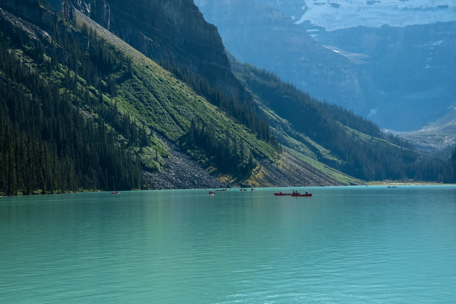A red canoe gliding across the turquoise water of Lake Louise