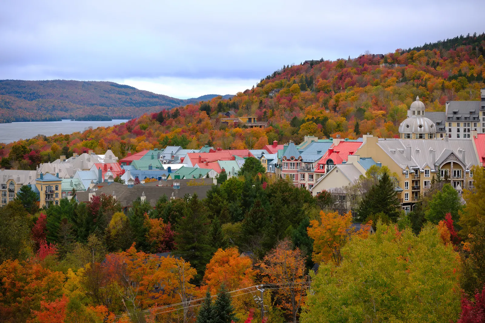 Autumn forest in red, orange and gold beside a lake in the Mont-Tremblant region of Quebec